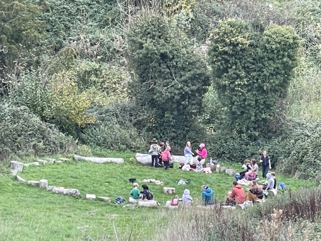 A group of people sitting together in a grassy circle on a farm