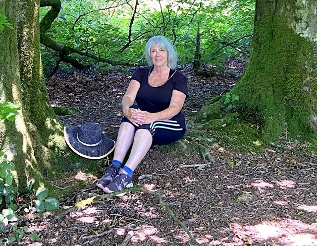 Chantal, workshop facilitator, smiling in a beautiful green forest